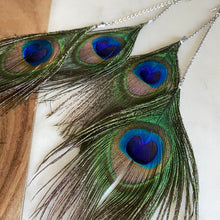 Load image into Gallery viewer, Close-up of Fauna cruelty free feather earrings made from gorgeous ethically sourced peacock feathers. Each earring features 2 peacock feathers, sterling silver chain, fold over clasps, o-rings, and french hook ear wires.