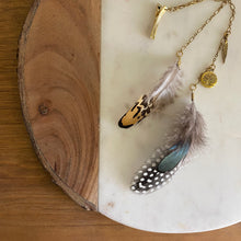 Load image into Gallery viewer, Close-up of Fauna cruelty free hair clip connecting 2 brass chains with 3 types of ethically sourced chicken feathers on each end. Also features 2 brass charms (a tree of life and a feather).