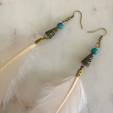 Load image into Gallery viewer, Close-up of Fauna cruelty free feather earrings made from ethically sourced goose feathers in a beautiful champagne peach color. Each earring features a brass cone cap with a wave design, an impression jasper bead, and raw brass French hook ear wire.
