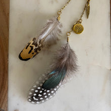 Load image into Gallery viewer, Close-up of Fauna cruelty free hair clip connecting 2 brass chains with 3 types of ethically sourced chicken feathers on each end. Also features 2 brass charms (a tree of life and a feather).
