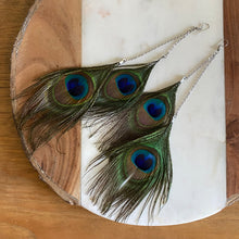 Load image into Gallery viewer, Close-up of Fauna cruelty free feather earrings made from gorgeous ethically sourced peacock feathers. Each earring features 2 peacock feathers, sterling silver chain, fold over clasps, o-rings, and french hook ear wires. 
