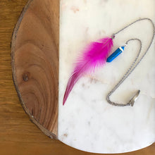 Load image into Gallery viewer, Close-up of Fauna hair clip jewelry made of 2 stainless steel chains with a cruelty free fuchsia rooster feather on one end and a faux turquoise pendant on the other.
