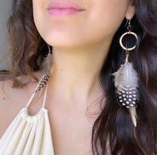 Load image into Gallery viewer, Woman wearing a Fauna eucalyptus and organic cotton maxi dress and cruelty free feather earrings made from 2 types of ethically sourced chicken feathers in the colors brown, beige, black, and white. Each earring also features raw brass fold over clasps, large recycled o-rings, smaller rings, and french hook ear wires. 
