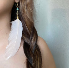 Load image into Gallery viewer, Woman wearing Fauna cruelty free feather earrings made from ethically sourced goose feathers in a beautiful champagne peach color. Each earring features a brass cone cap with a wave design, an impression jasper bead, and raw brass French hook ear wire.
